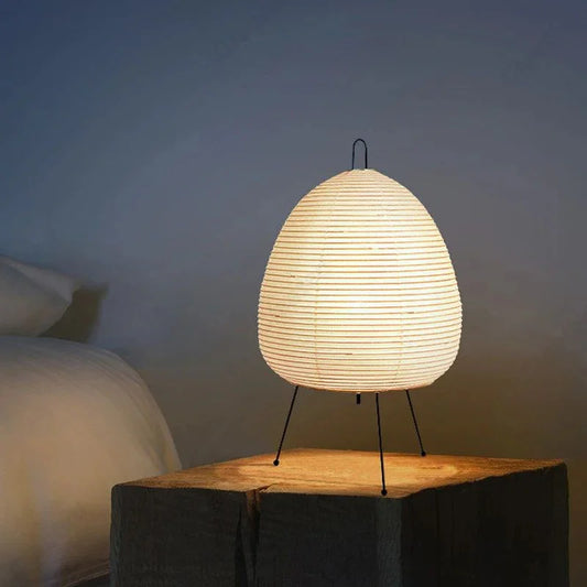 Modern paper lantern table lamp with tripod legs on wooden bedside table