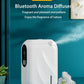 White Bluetooth aroma diffuser emitting mist on teal surface, surrounded by white flowers, modern home decor