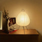 Modern paper lantern table lamp with tripod legs on wooden nightstand in cozy home decor setting
