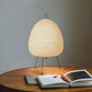 Modern paper lantern table lamp on wooden desk with open book and pencils, minimalist decor